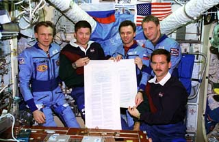 Crewmembers with a scroll they signed commemorating the 50th anniversary of the United Nations 